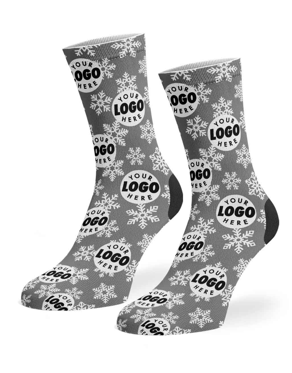 A pair of gray crew socks with a white snowflake pattern and a repeating circular placeholder logo design that reads 'YOUR LOGO HERE', shown on a plain white background.