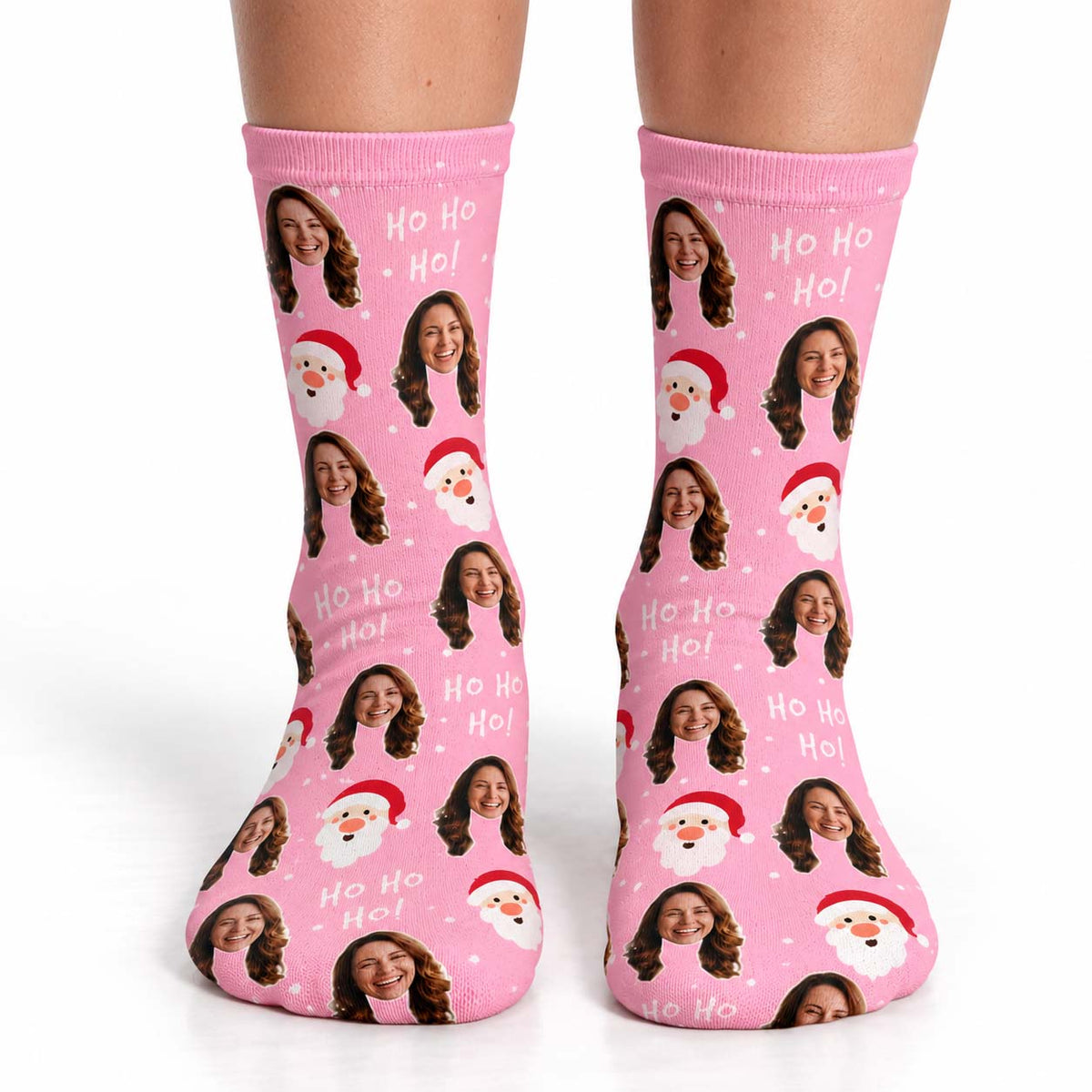 A pair of pink crew socks with a repeating pattern of custom photos of a woman, Santa Claus, and 'Ho Ho Ho!' text, shown on a white background with the model's legs visible.